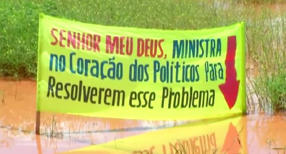 Faixa pede ajuda de Deus para problemas de alagamento. Imagens: TV Anhanguera/Globo.